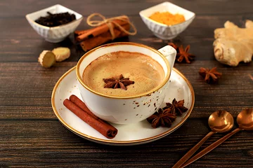 Foto op Plexiglas anti-reflex Indian masala chai tea with milk, ginger, anise and cinnamon on an old wooden table. Traditional drink with spices, cafe concept, advertising for restaurant and menu © Светлана Балынь