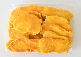 Dry mango in a plastic container on a light background