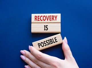 Recovery is possible symbol. Concept words Recovery is possible on wooden blocks. Beautiful deep blue background. Businessman hand. Business and Recovery is possible concept. Copy space.