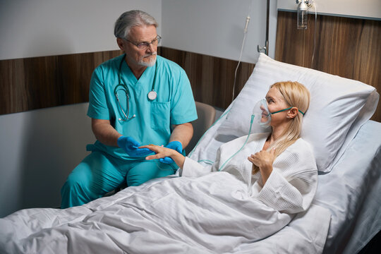 Caring attending physician comforting hospitalized woman during IV therapy