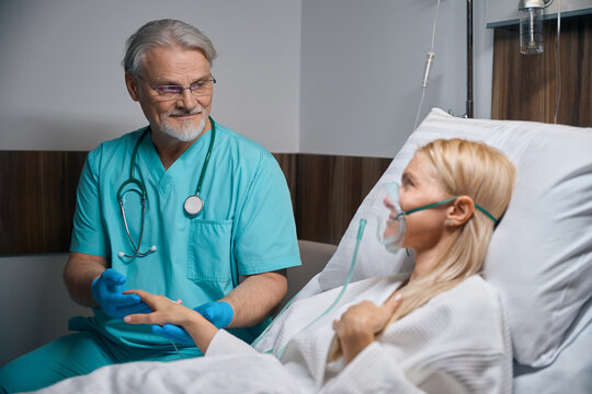 Doctor supporting inpatient during intravenous infusion procedure in ward