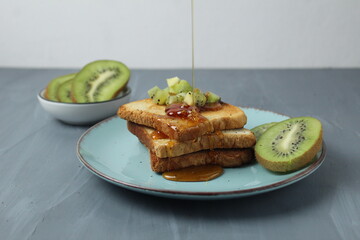 Honey poured on toast with fruit on a plate on a gray background with space for copyspace text. Healthy breakfast