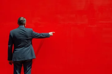 Zelfklevend Fotobehang Man in Suit Pointing at Red Wall © olegganko
