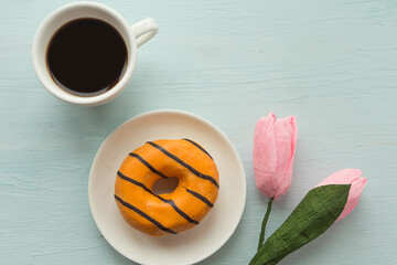 Donut and coffee cup on wooden background, top view