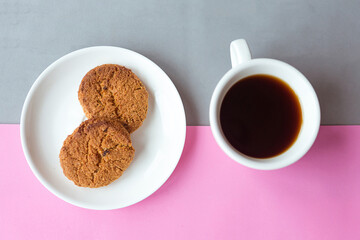 Coffee cup and raisin cookies on gray and pink pastel background. Minimal concept.