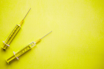 two syringes on yellow background. covid19 concept