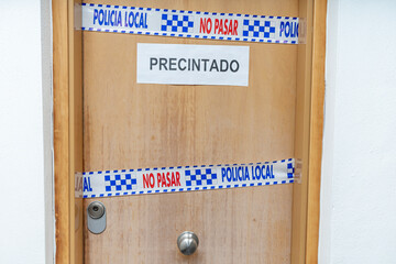 A sealed house by the Local Police in Spain with police tape on the door with the text: sealed, do not cross, Local Police. - obrazy, fototapety, plakaty
