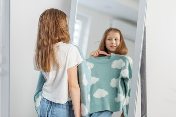 Child Girl Contemplating Clothing Choice in Mirror. Morning preparation before school.