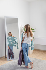 Choosing Outfits: Child with Clothes by Mirror. Morning preparation before school.