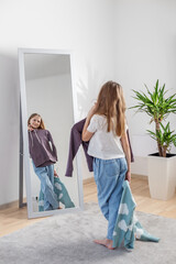Choosing Outfits: Child with Clothes by Mirror. Morning preparation before school.