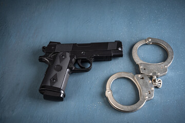Gun and handcuffs on blue background, stock photo, criminal concept