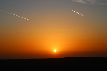 airplane and its trail in the sky. clouds and different color tones in the sky at sunset. Amazing and incredible sunset.