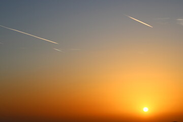 airplane and its trail in the sky. clouds and different color tones in the sky at sunset. Amazing...