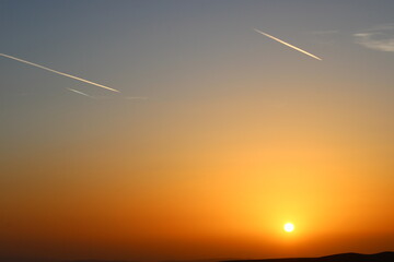 airplane and its trail in the sky. clouds and different color tones in the sky at sunset. Amazing...