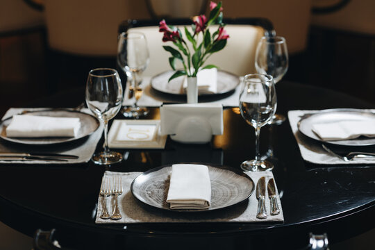 Beautifully organized event - round served table banquet ready for guests, round decorated table with empty plate, glasses, forks, napkin. Elegant dinner table 