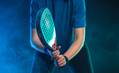 Close-up photo of padel tennis player with racket on tournament. Girl athlete with paddle racket on court with neon colors. Sport concept. No face. - 778501483