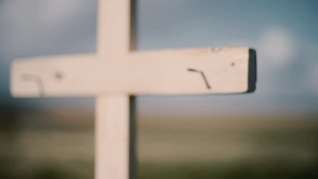 Wooden cross with nails in a field on sunny day close up. Sun silhouette.