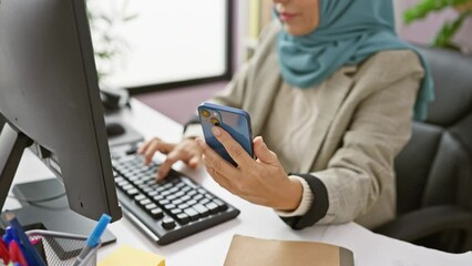 A professional woman at indoor office using smartphone and computer, with blurred interior background. - Powered by Adobe