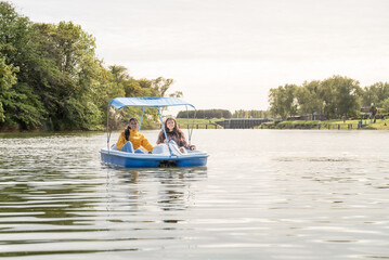 Fototapeta na wymiar mother and daughter riding a pedal boat on the river enjoying the day off
