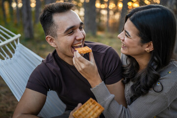 Couple adult man and woman in love eat waffle in nature park or woods