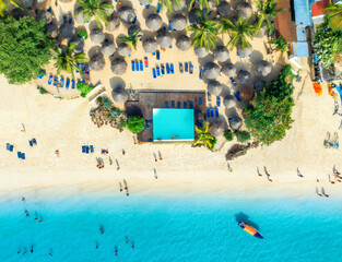 Aerial view of pool, white sandy beach with palms, umbrellas, swimming people, boat, blue ocean, at sunset. Summer vacation in Nungwi, Zanzibar island. Tropical landscape. Clear azure sea. Top view - 778510847