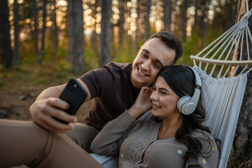 Man and woman young adult couple in nature listen music headphones