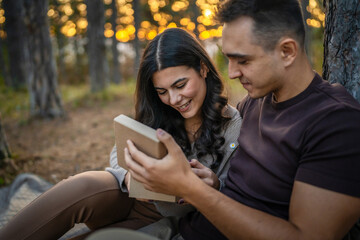 Young couple man and woman give present gift box while sit in nature