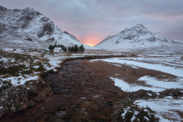 A remote hut and calm river at the foot of Buachaille Etive Mor at the entrance to the valley of Glencoe in the Scottish Highlands, Scotland