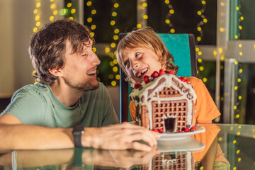 Savor unique moments as dad and son bite into an unconventional gingerbread house, adding a twist to Christmas traditions. A tasty blend of creativity and family joy