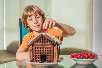 Immerse in festive delight as a boy crafts boy crafting an unconventional gingerbread house, infusing Christmas with unique creativity and festive cheer. A sweet scene of seasonal bonding and culinary