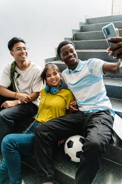 Happy classmates friends taking photo selfie with phone in the stairs of Secondary School