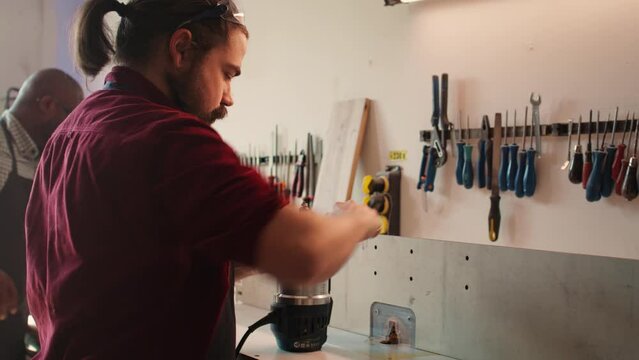 Mechanic in carpentry shop changing rotor part on spindle moulder machinery. Repairman in joinery fixing broken wood shaper, replacing damaged component, camera B close up shot