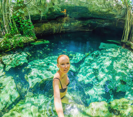 Woman immersed in the enchanting beauty of a Mexican cenote, surrounded by crystal-clear waters and captivating natural formations