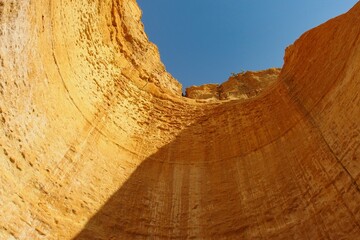 View from below to the blue sky, surrounded by the golden yellow inner cave walls of the Algarve in...