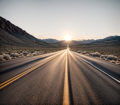 A desert road with mountains in the background at sunset.