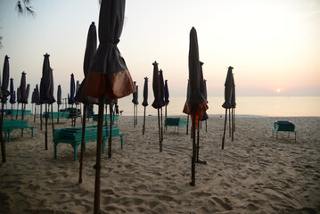 A silhouette at beach deck chairs and umbrella in the morning at Cha-am Beach. Located at Phetchaburi Province in Thailand.