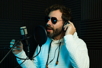 Male singer with sunglasses during a recording session in a studio - 778537627