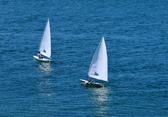 two small sailboats tacking across the bay