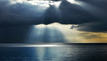 Ocean illuminated by sunlight breaking through dark clouds, creating a dramatic seascape - obrazy, fototapety, plakaty