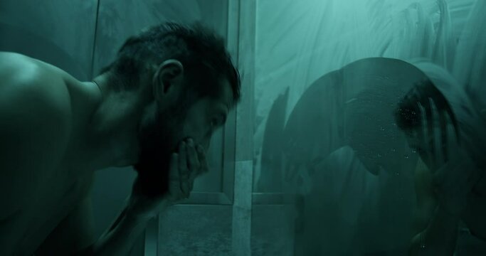Lonely man washing face in front of mirror in bathroom