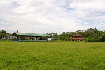 Covered sports court at the edge of a large field in Puerto Bolivar, in the Cuyabeno Wildlife Reserve, outside of Lago Agrio, Ecuador - obrazy, fototapety, plakaty