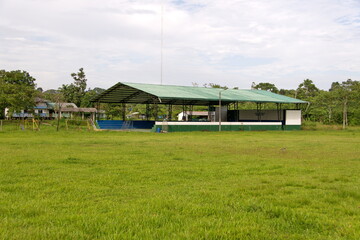 Fototapeta na wymiar Covered sports court at the edge of a large field in Puerto Bolivar, in the Cuyabeno Wildlife Reserve, outside of Lago Agrio, Ecuador