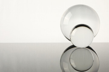 Transparent glass balls on mirror surface against light background. Space for text
