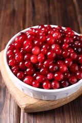 Fresh ripe cranberries in bowl on wooden table, closeup