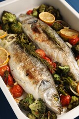 Delicious fish with vegetables and lemon in baking dish on table, closeup