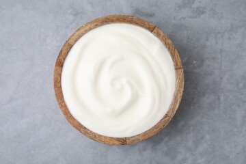 Delicious natural yogurt in bowl on grey table, top view
