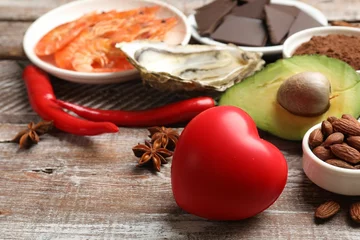 Gordijnen Natural aphrodisiac. Different food products and heart model on wooden table, closeup © New Africa