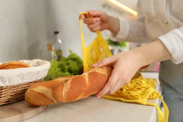 Fotobehang Woman taking baguette out from string bag at countertop, closeup © New Africa