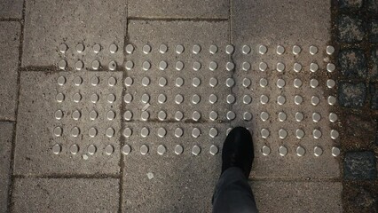 Cityscape inclusiveness: Bird's-eye view of tactile pavement with braille, promoting accessibility for visually impaired individuals in the city