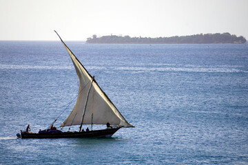 Dhow sailing on a calm sea with an island in the distance